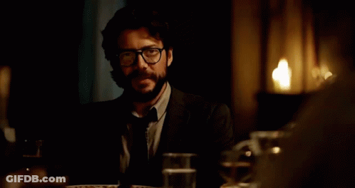 A Man In A Vest And Tie Sitting At A Table GIF