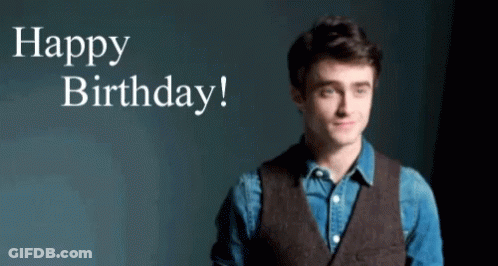 A Man In A Vest Is Standing In Front Of A Sign That Says Happy Birthday ! GIF
