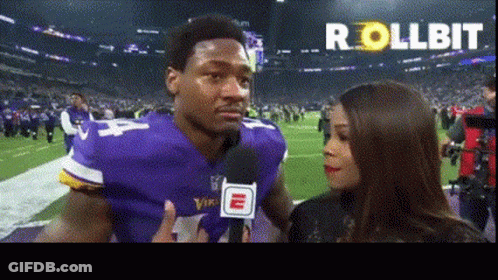 A Man In A Vikings Jersey Is Talking Into A Microphone GIF