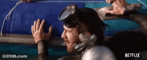 A Man In A Wet Suit And Goggles Is Reaching For A Raft . GIF