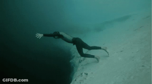 A Man In A Wetsuit Is Swimming In The Ocean GIF