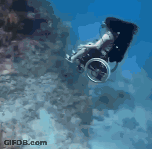 A Man In A Wheelchair Is Swimming Underwater GIF