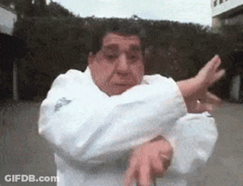 A Man In A White Adidas Jacket Is Doing A Karate Move GIF