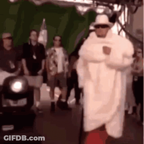 A Man In A White Coat And Hat Is Standing In Front Of A Crowd . GIF