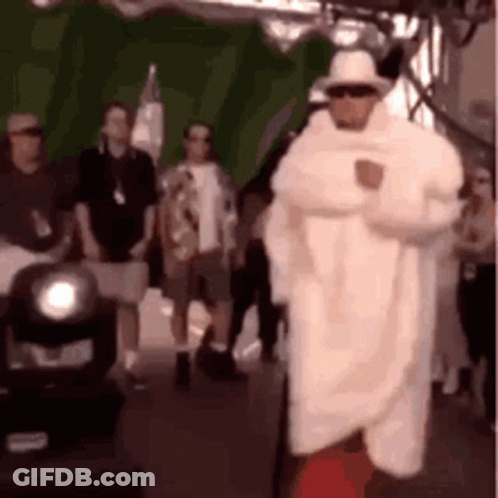 A Man In A White Coat And Hat Is Standing In Front Of A Green Screen . GIF