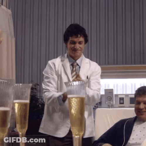 A Man In A White Coat And Tie Is Pouring A Glass Of Beer GIF