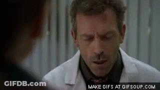 A Man In A White Coat And Tie Is Talking To Another Man In A Black Shirt . GIF