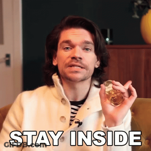 A Man In A White Coat Is Holding A Glass With The Words Stay Inside Above Him GIF