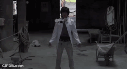 A Man In A White Coat Is Standing In A Dark Room With His Arms Outstretched And A Red Light Coming Out Of His Chest GIF