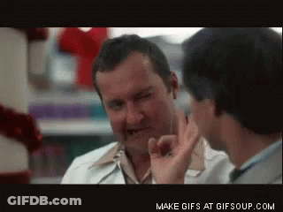 A Man In A White Coat Is Talking To Another Man In A Store GIF