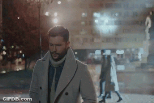 A Man In A White Coat Is Walking Down The Street GIF