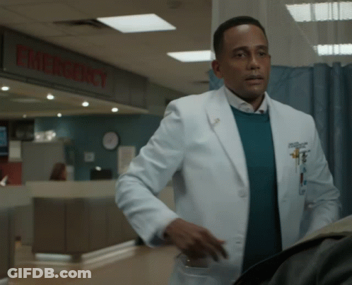 A Man In A White Coat Stands In Front Of An Emergency Room GIF