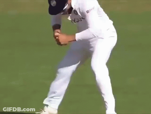 A Man In A White Cricket Uniform Is Standing On A Field And Screaming . GIF