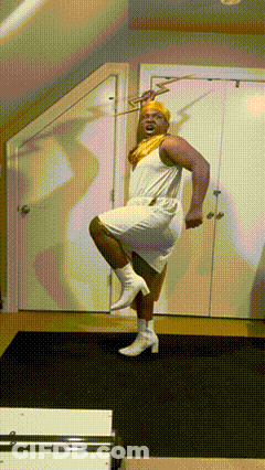 A Man In A White Dress Holds A Trumpet In His Hand GIF