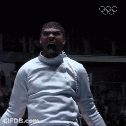 A Man In A White Fencing Uniform Is Screaming With The Olympics Logo In The Background GIF