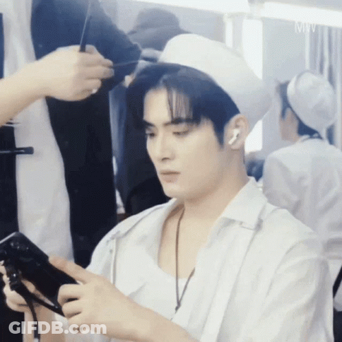 A Man In A White Hat Is Holding A Cell Phone GIF