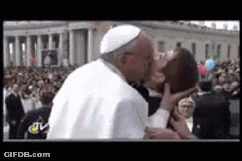 A Man In A White Hat Is Kissing Another Man In Front Of A Crowd Of People . GIF