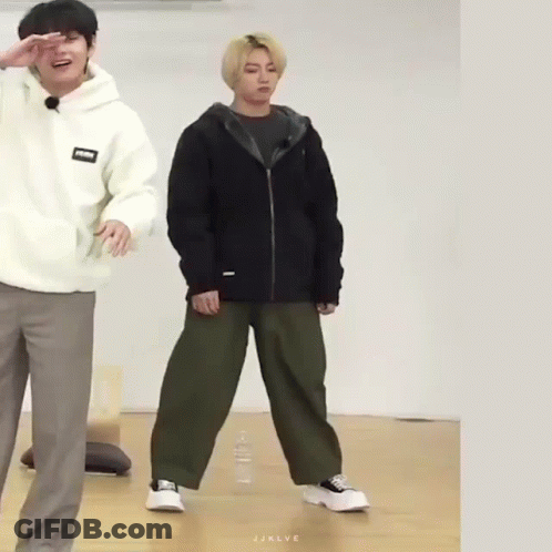 A Man In A White Hoodie And A Man In A Black Jacket Are Standing Next To Each Other On A Wooden Floor . GIF