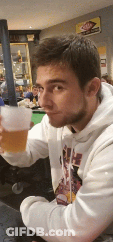A Man In A White Hoodie Is Holding A Glass GIF