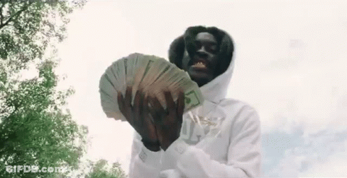 A Man In A White Hoodie Is Holding A Large Stack Of Money In His Hands . GIF