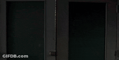 A Man In A White Hoodie Is Looking Out A Window GIF