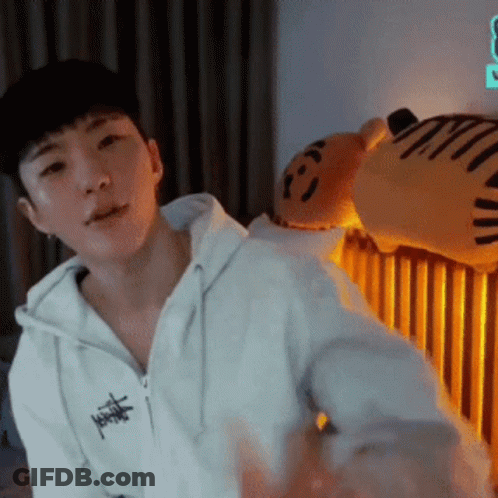 A Man In A White Hoodie Is Standing In Front Of A Stuffed Animal . GIF