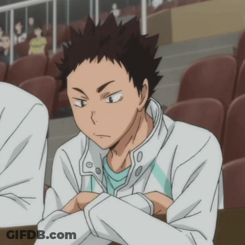 A Man In A White Jacket And A Blue Shirt Is Sitting In A Stadium GIF