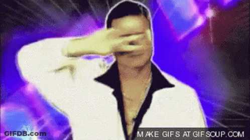 A Man In A White Jacket Is Covering His Face With His Hand . GIF