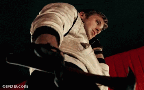 A Man In A White Jacket Is Holding A Hammer In Front Of A Red Curtain GIF