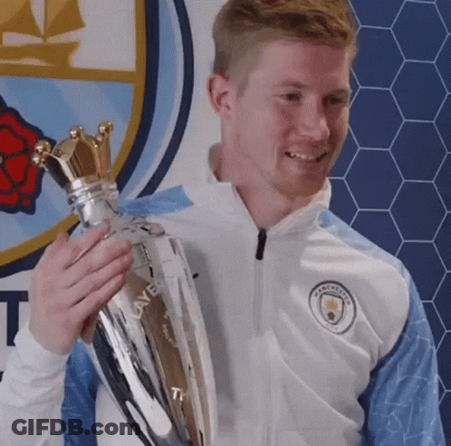 A Man In A White Jacket Is Holding A Trophy In His Hands . GIF