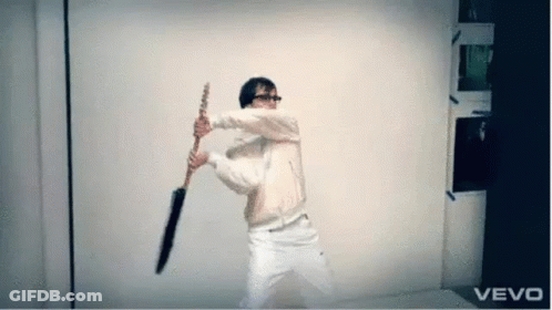 A Man In A White Jacket Is Holding An Umbrella In Front Of A Vevo Logo . GIF