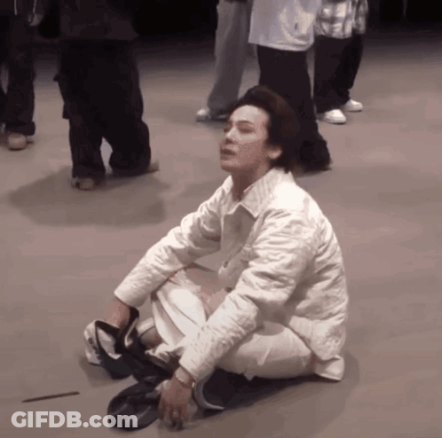 A Man In A White Jacket Is Kneeling Down On The Floor GIF