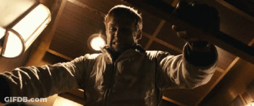 A Man In A White Jacket Is Pointing At The Camera GIF
