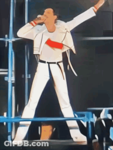 A Man In A White Jacket Is Singing Into A Microphone On A Stage GIF