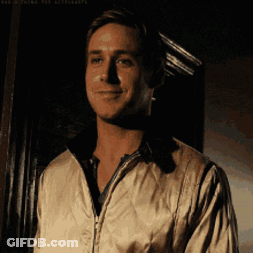 A Man In A White Jacket Is Smiling In Front Of A Black Wall GIF