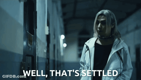 A Man In A White Jacket Is Standing In A Dark Hallway With The Words Well That 'S Settled Below Him GIF