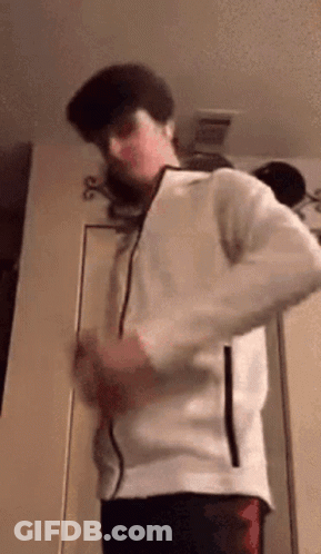 A Man In A White Jacket Is Standing In A Room . GIF