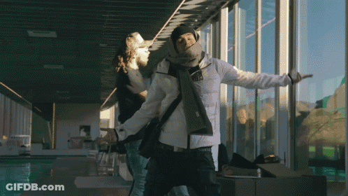 A Man In A White Jacket Is Standing In Front Of A Large Window GIF
