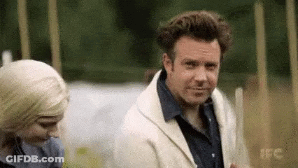 A Man In A White Jacket Is Standing Next To A Woman . GIF