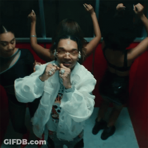A Man In A White Jacket Is Surrounded By Women In Black Dresses GIF