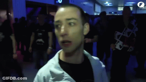 A Man In A White Jacket Stands In A Crowd Of People With The Letter F In The Corner GIF