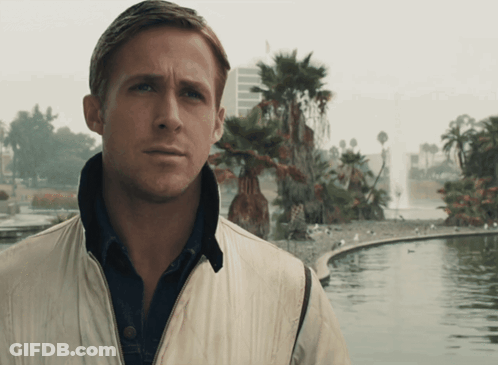 A Man In A White Jacket Stands In Front Of A Pond With Palm Trees In The Background GIF