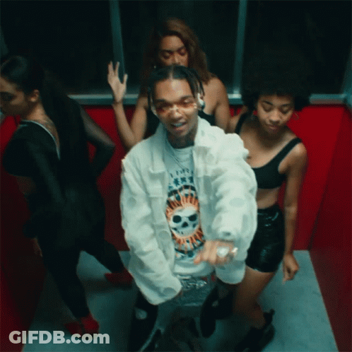 A Man In A White Jacket With A Skull On His Shirt Is Surrounded By Women GIF