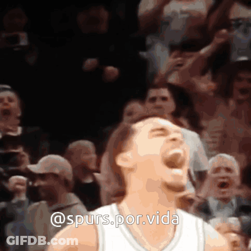 A Man In A White Jersey Is Screaming In Front Of A Crowd With The Words @Spurs.por.vida Above Him GIF