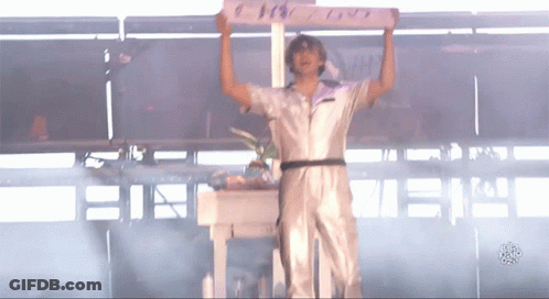 A Man In A White Jumpsuit Is Holding Up A Sign That Says ' I Love You ' On It GIF