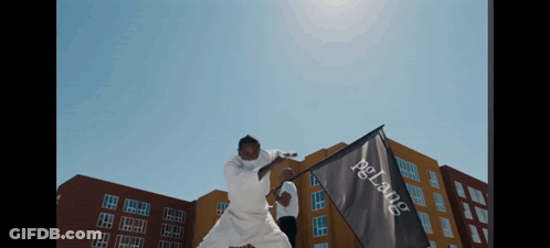 A Man In A White Karate Uniform Is Holding A Flag That Says Pelang On It GIF