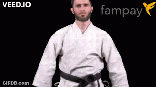 A Man In A White Karate Uniform With A Black Belt Is Standing In Front Of A Fampay Logo GIF