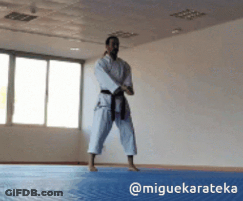 A Man In A White Karate Uniform With A Black Belt GIF