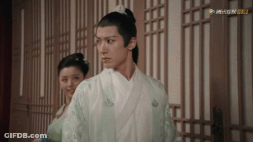A Man In A White Kimono Is Standing Next To A Woman In A Green Dress .. GIF