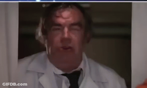 A Man In A White Lab Coat And Tie Is Looking Out A Window . GIF